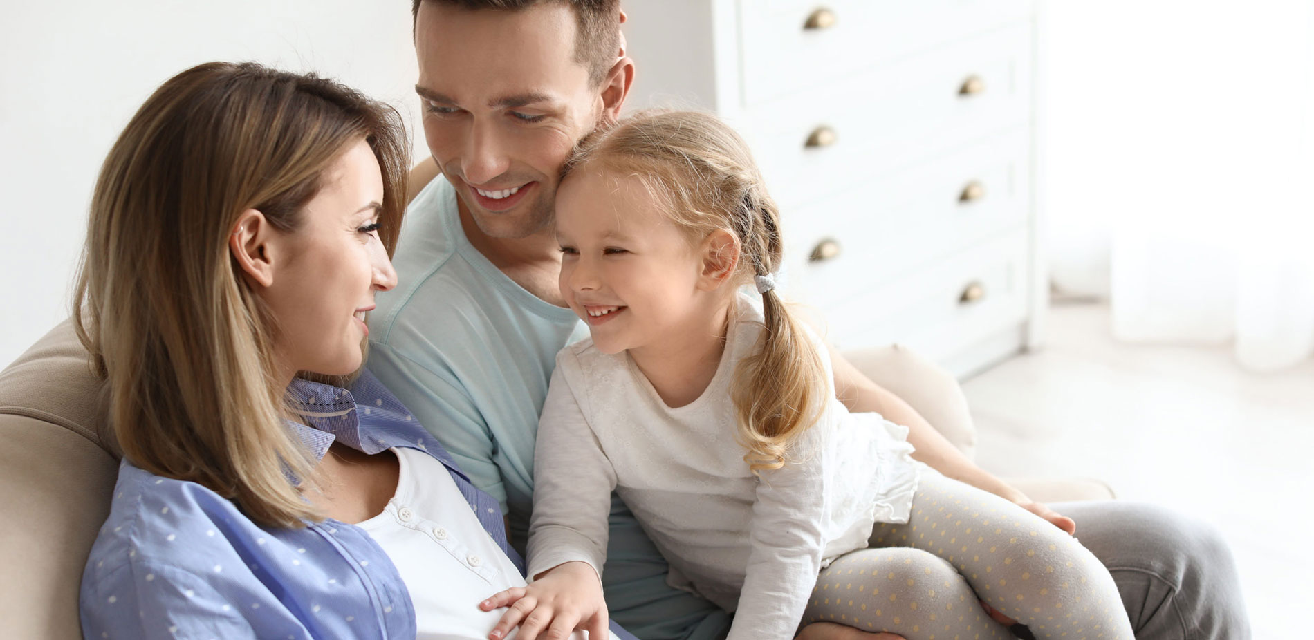 Little girl feels mom's pregnant stomach with dad